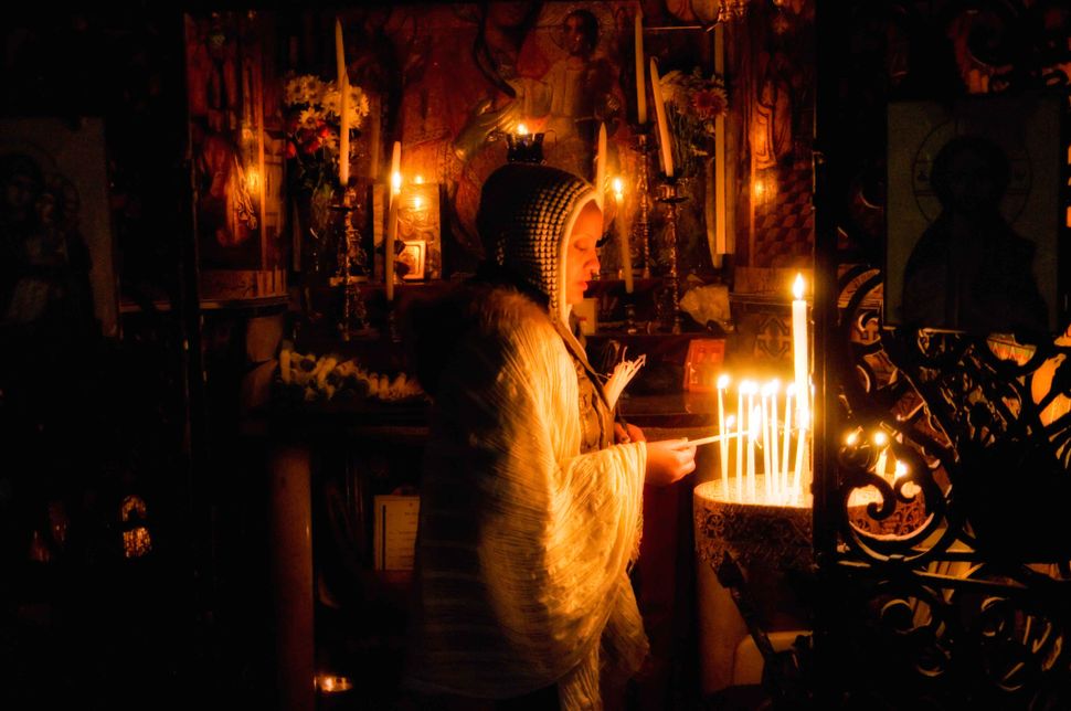 Believer lighting a candle at the Edicule of the Holy Sepulchre, Jerusalem